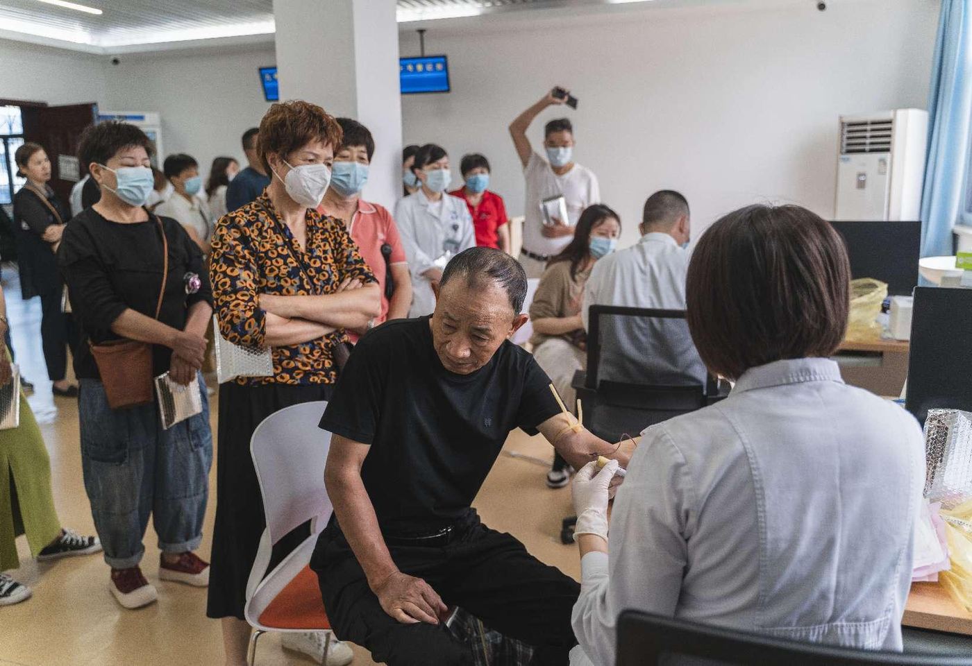 Residents queue for blood-draw screening at a community health event